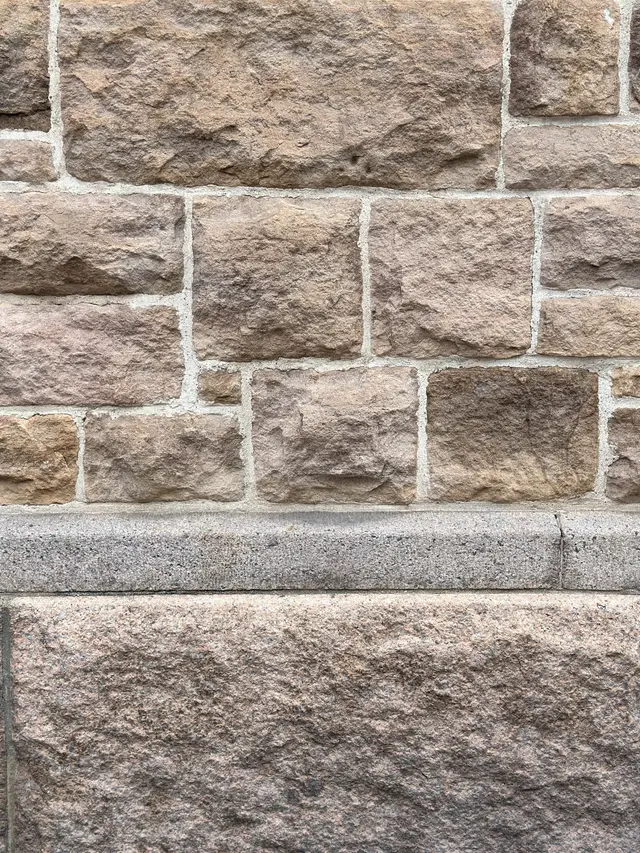 The granite plinth where it meets the brick above it.