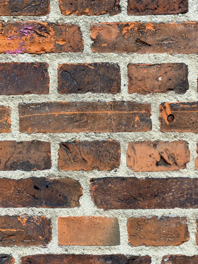 Red brick close to, the mortar joints and the weathering of the surface visible.