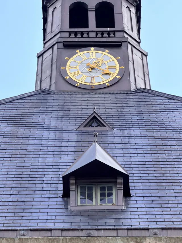 The clock face with its gilded hands on the slate face of the tower.