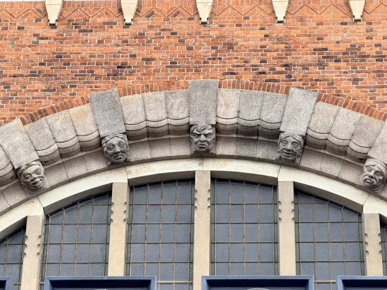 Human masks carved beside a round-arched window.