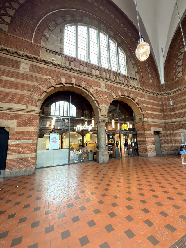 Brick-and-stone arches inside the station with glazed shopfronts below and a tall semicircular window above.