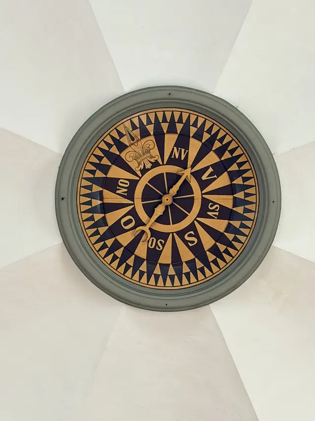 The wind rose in the vestibule vault: a gold and dark blue compass card with the Danish points, and a separate pointer on a spindle.