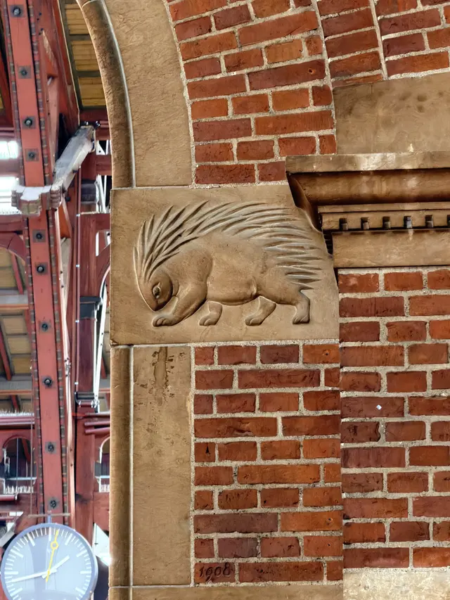 A hedgehog with its spines clearly cut, on a projecting sandstone block where an arch lands.