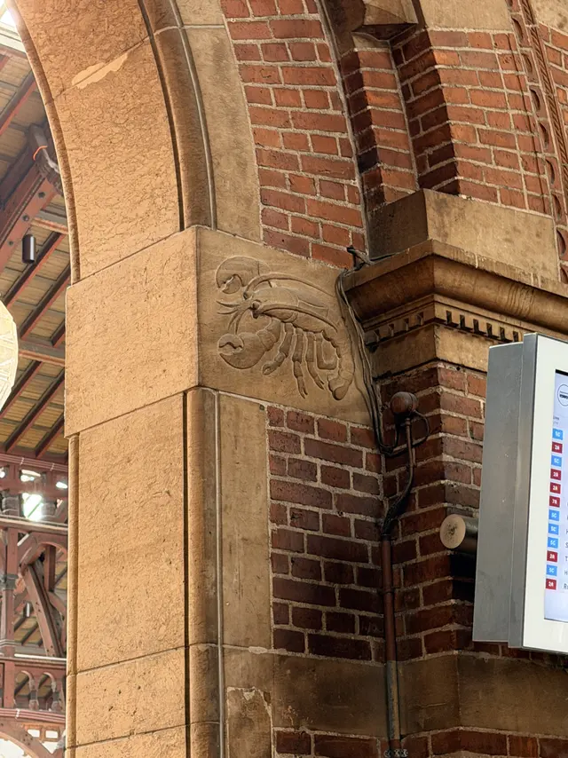 A crayfish with claws and antennae carved on a projecting sandstone corner block.