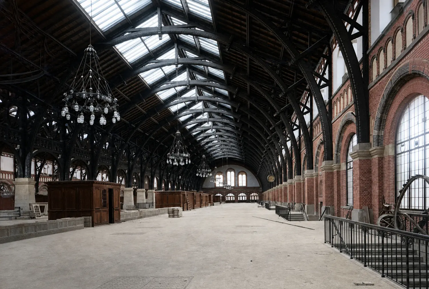 The finished main hall from inside, still empty, with timber arches, rooflights along the ridge and large chandeliers over a bare floor.