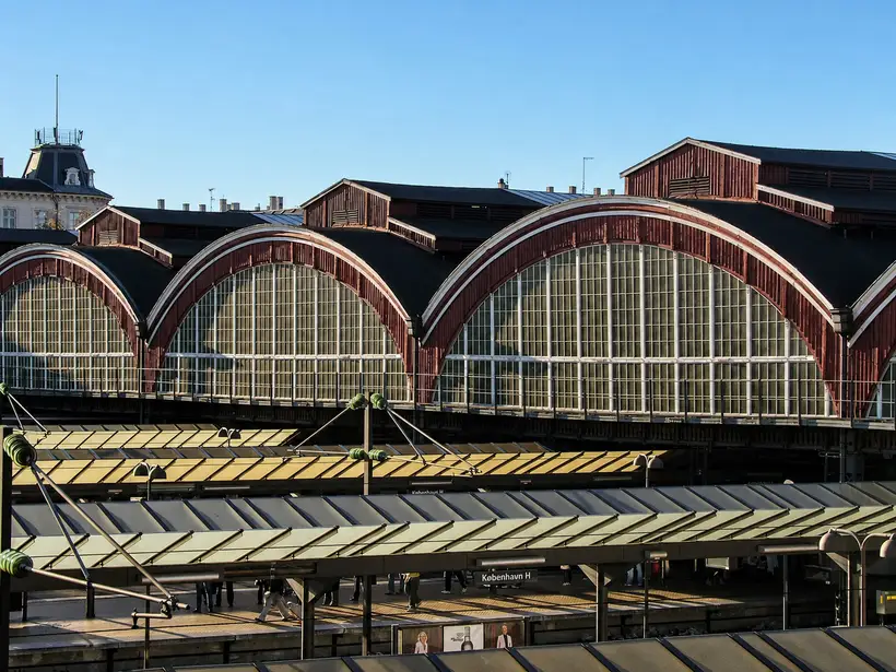 Large semicircular gables of red-painted timber with white glazing bars. Two flat platform canopies run beneath them.