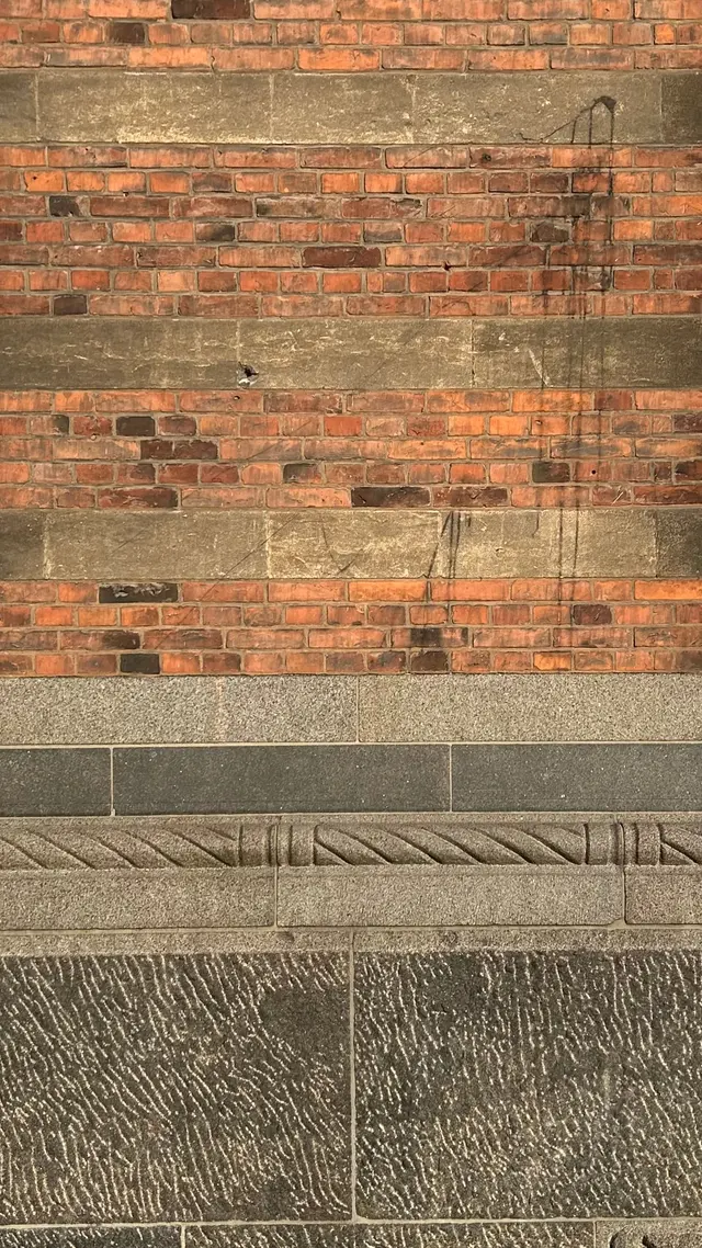 Detaljefoto af tegl kalksten granit mur lagdeling på gadefacaden, i tegl, mørtel og granit.