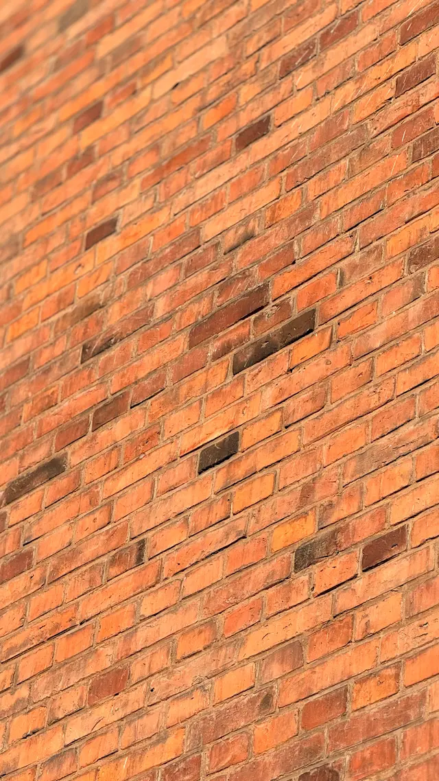 Detaljefoto af meleret tegl i strejf lys på gadefacaden, i tegl og mørtel.