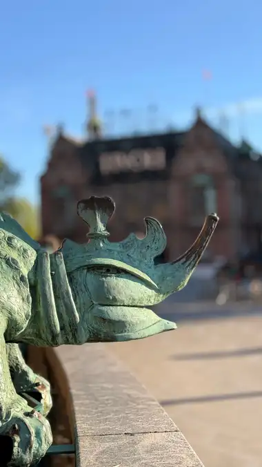 Nærbillede af kronet dyr hoved på terrasse balustrade set fra pladsen, i kobber, jern og natursten.