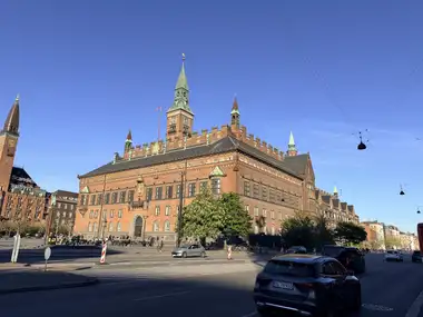 Oversigtsbillede af hel bygning fra  boulevard hjørne set fra pladsen, i tegl, natursten, skifer og kobber.