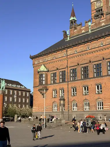 Oversigtsbillede af plads front under en tindekranset krone set fra pladsen, i tegl, natursten, skifer og kobber.