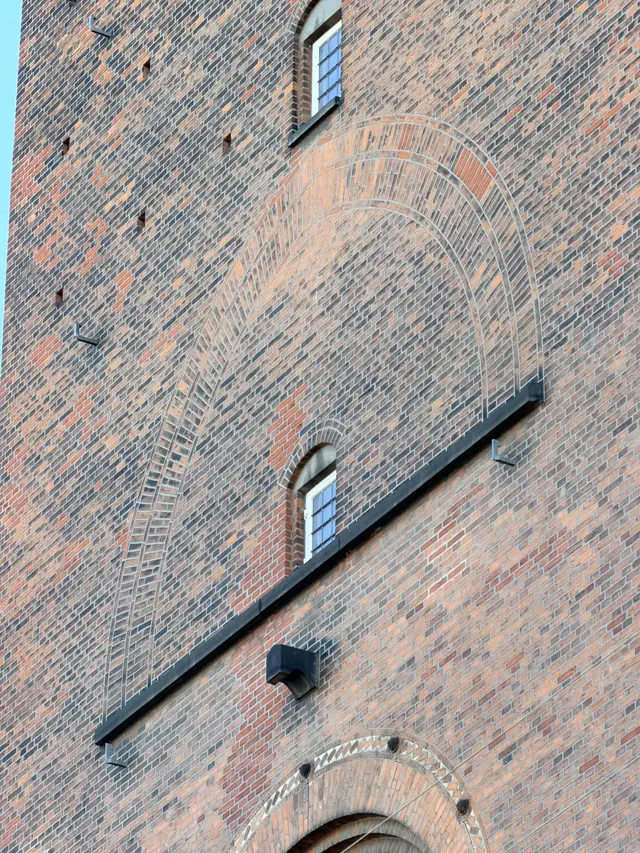 Detaljefoto af flammet og rød tegl af en glat mur på gadefacaden, i tegl, mørtel, træ og glas.