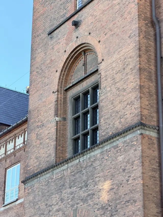 Billede af tårn vindue i flammet murværk på gadefacaden, i tegl, mørtel, natursten og glas.