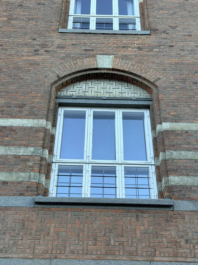 Billede af vindue fag med flettet tegl felter i gården, i tegl, mørtel, granit og natursten.