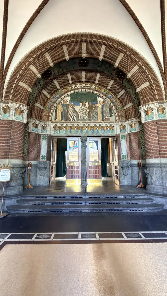 Billede af indgang relief med  valgsprog i forhallen, i tegl, natursten, glas og træ.