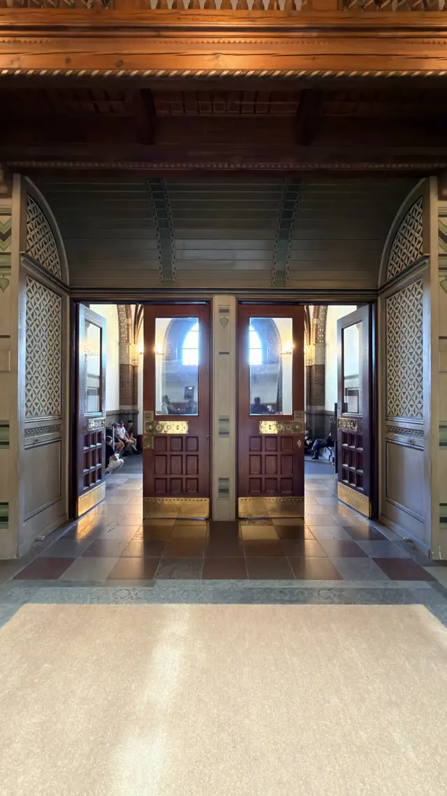 Billede af vestibule døre med messing plader under udskåret træ loft i forhallen, i træ, glas, natursten og fliser.