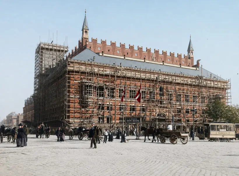 Billedet viser Københavns Rådhus under opførelse i 1897 med J. Schannongs stenhuggeri, udstillede gravmonumenter og en sporvogn til højre.
