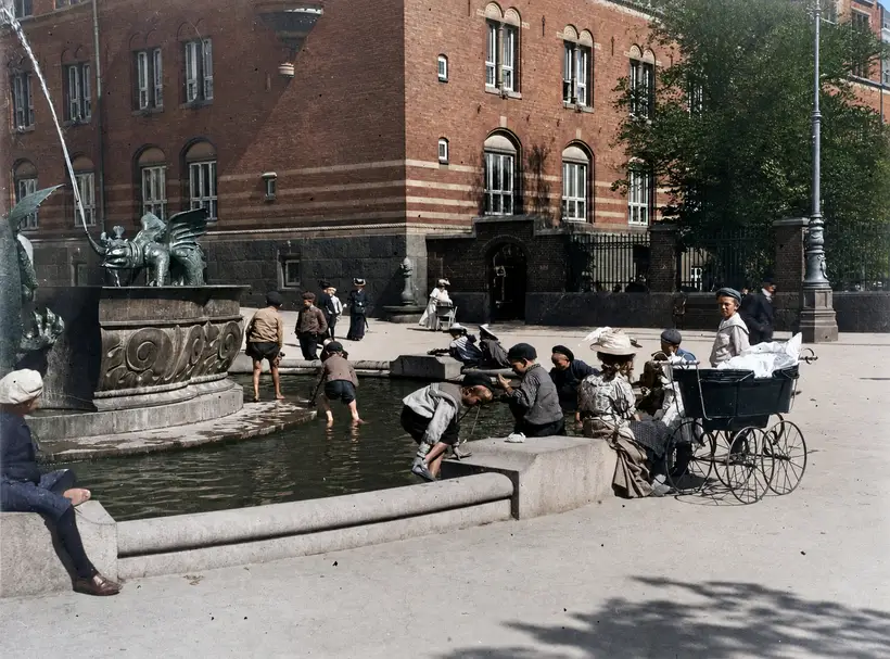 Billedet viser folk, der sopper i Dragespringvandet på Rådhuspladsen foran Københavns Rådhus i 1912.