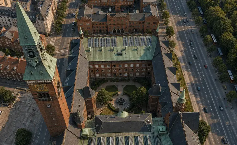 Københavns Rådhus set næsten lodret fra luften med tårnet, kobbertage, skifertage og den indre gård omgivet af det centrale København.