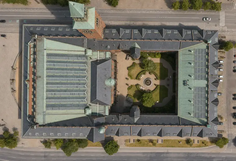 Næsten lodret luftfoto af Københavns Rådhus med tårn, kobbertage, glasoverdækninger og den grønne indre gård.