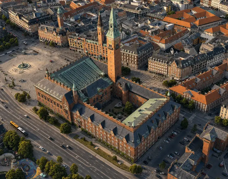 Skråt luftfoto af Københavns Rådhus med tårn, gårdrum og kobbertage midt i det centrale København.