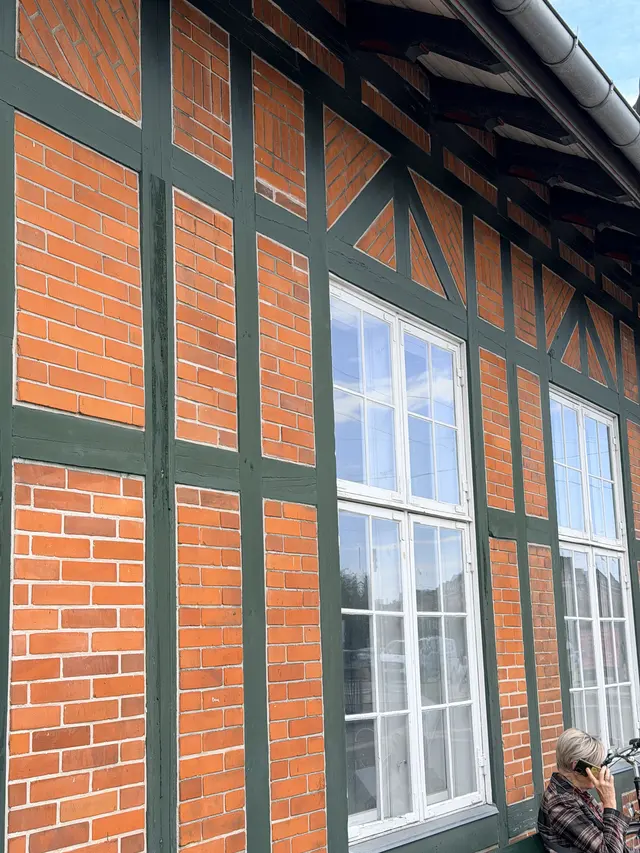 Panels of red brick between green timbers, laid in different patterns.