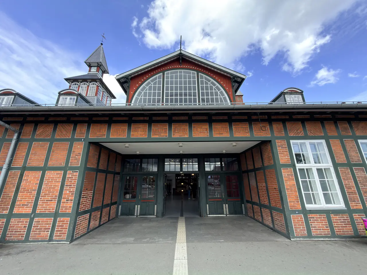 The central entrance on the street front: a timber-framed bay with glazed doors under the lunette gable.