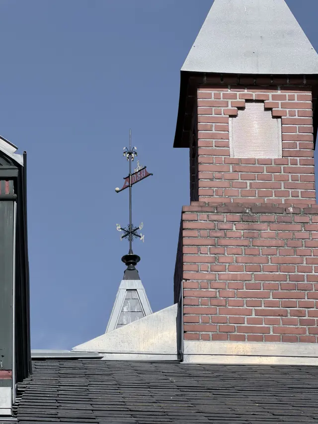 The weathervane on the spire: a crown over the letters DSB, with compass arms below.
