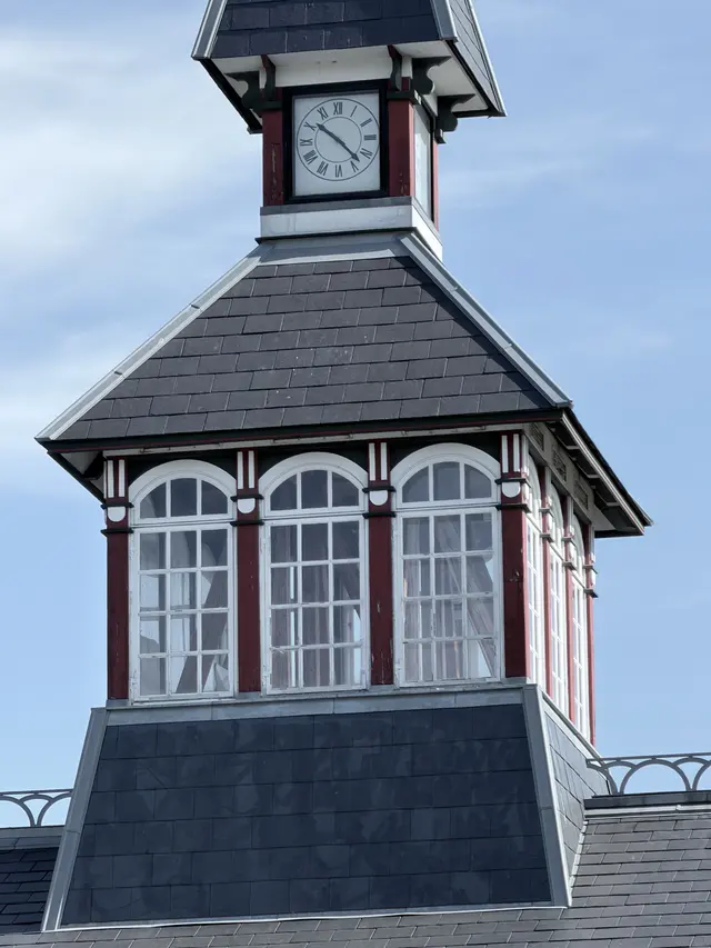 The tower close up: a clock, a row of small arched windows and the slate spire.