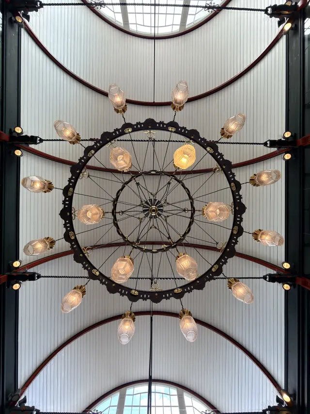A chandelier seen from directly below: an iron ring with glass lamps against the boarded vault.