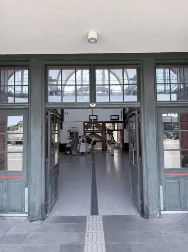 A green-painted glazed timber entrance with open double doors and a multi-pane transom frames a view into the station concourse.