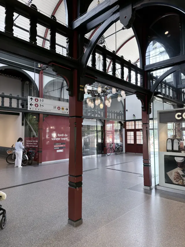 The two-storey timber arcade along a hall, painted red and green.