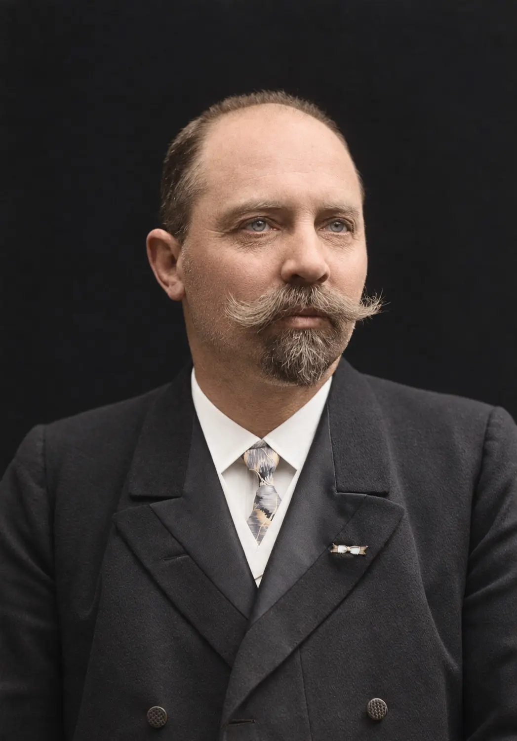 Studio portrait of N.C. Monberg, a man with a waxed moustache and pointed beard in a dark double-breasted jacket.