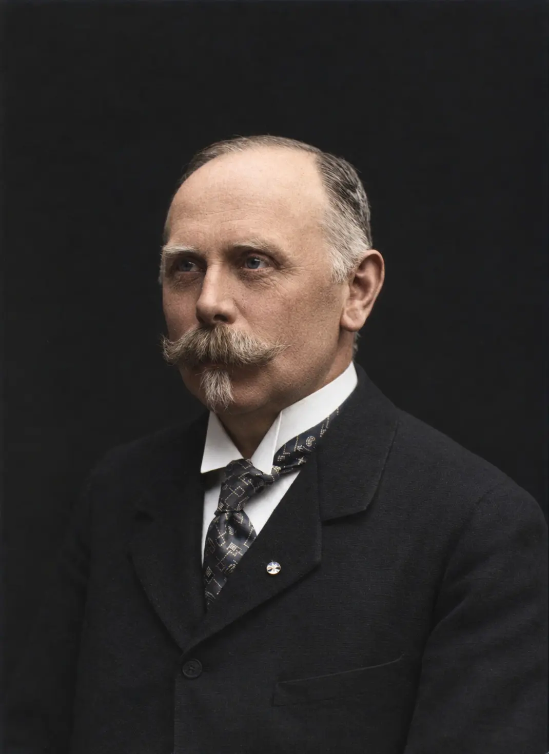 Studio portrait of Heinrich Wenck, a balding man with a heavy moustache and pointed beard in a dark suit and patterned tie.