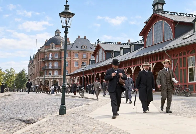 Østerport Station’s long platform building faces a cobbled forecourt where pedestrians, bicycles, horse-drawn carriages and street lamps gather.