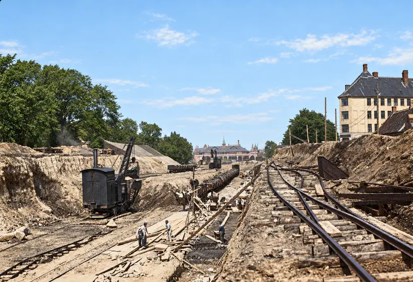 Workers, cranes and temporary rail tracks fill a deep cutting, with København Østerport Station visible in the distance.