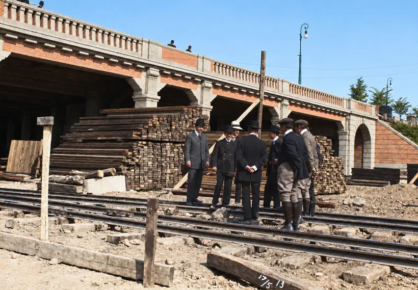 Engineers stand on railway tracks beside stacked timber and a masonry viaduct during construction of the Boulevard Railway.