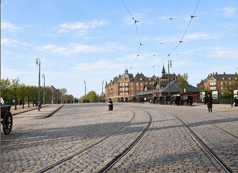 Østerport Station stands beside a broad cobbled approach with curving tram tracks, overhead wires, pedestrians, cyclists and early motor vehicles.