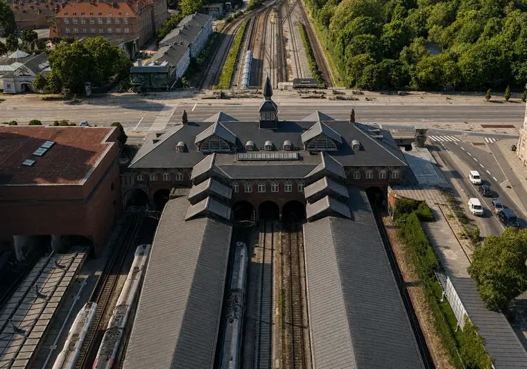 The station building and long platform roofs seen obliquely from above, surrounded by tracks, a broad street and green areas.