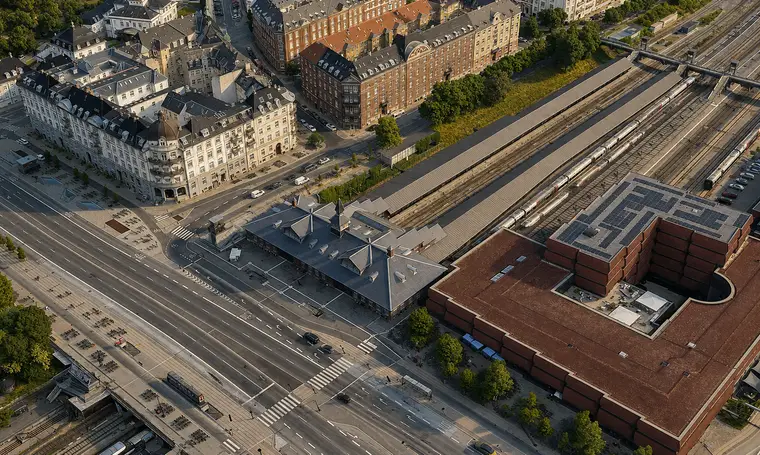 The station building stands between a broad road junction, multiple railway tracks and dense urban blocks.