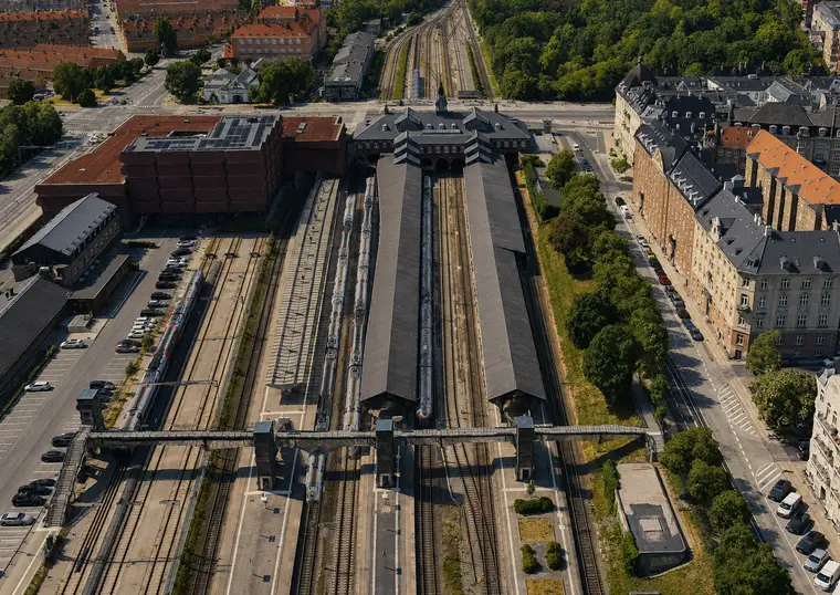 The station building, platform roofs, trains and extensive railway tracks set between urban blocks and green areas.