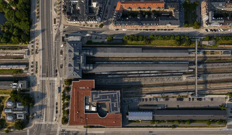 The station building and long covered platforms sit between railway tracks, broad roads and dense city blocks.