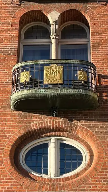 Billede af forgyldt altan smedejern på gadefacaden, i tegl, mørtel, jern og kobber.
