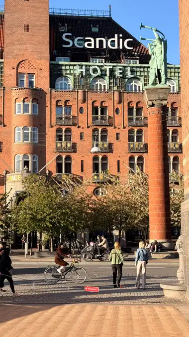 Oversigtsbillede af bronze lur blæsere set fra pladsen, i tegl, natursten, kobber og fliser.