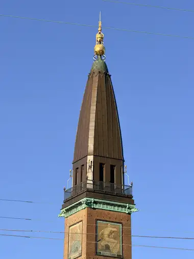 Billede af palace hotel tårn spir set fra pladsen, i tegl, kobber, metal og jern.