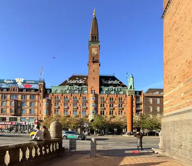 Oversigtsbillede af palace hotel front facade set fra pladsen, i tegl, granit, fliser og kobber.