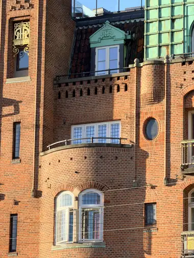 Billede af buet tegl altan fag på gadefacaden, i tegl, natursten, træ og glas.