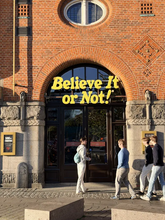 Gule neonbogstaver, der læser Believe It or Not!, sat ind i Rosens granitportal under et ovalt vindue. Nederst til venstre ses et hugget hoved på pillen.