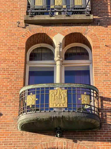 Billede af forgyldt altan gelændere på gadefacaden, i tegl, mørtel, granit og træ.