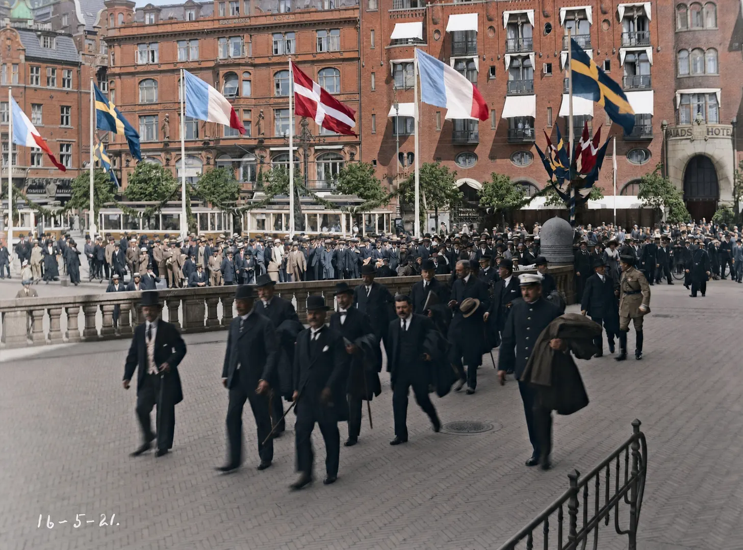 Den franske kommunaldelegation fotograferet ved Paladshotellet i 1921, en gruppe mænd i frakker og hatte foran hotellets facade.